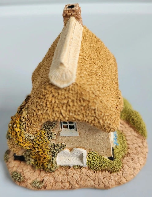 Textured house-shaped object with a pointed roof on a light gray background