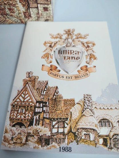 A printed card or booklet cover featuring a cream background with an illustrated village scene in brown, beige, and gray tones. A central crest reads 'Hilpertlano' with the motto 'Parvus est bellus,' and '1988' appears at the bottom.