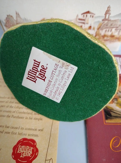 A green felt-covered hand mirror with a gold-toned metal edge, featuring a white paper label that reads 'Lilliput Lane' and 'WHEYSIDE COTTAGE'.