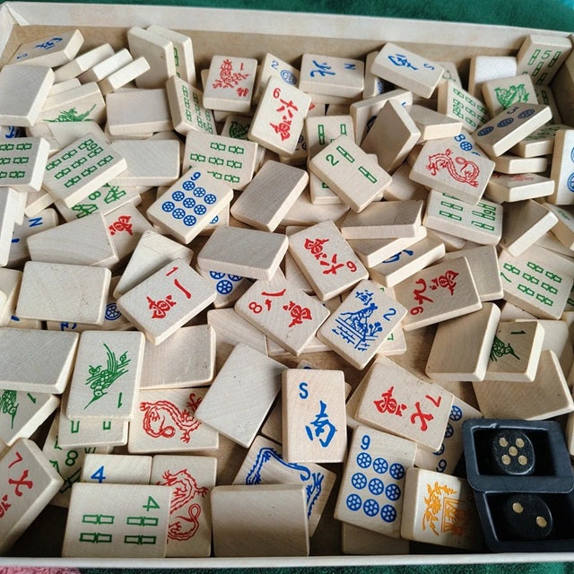 Collection of wooden Mahjong tiles with various symbols in a box.