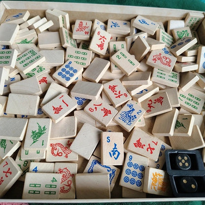 Collection of wooden Mahjong tiles with various symbols in a box.