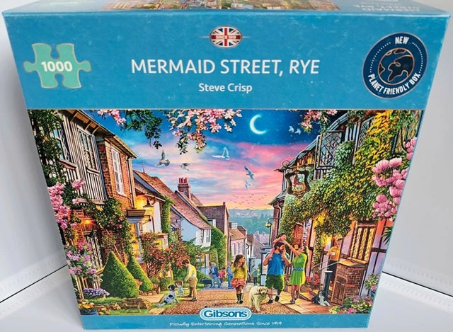 Jigsaw puzzle box featuring a scenic village scene with 'Mermaid Street, Rye' and 'Steve Crisp' on the packaging.