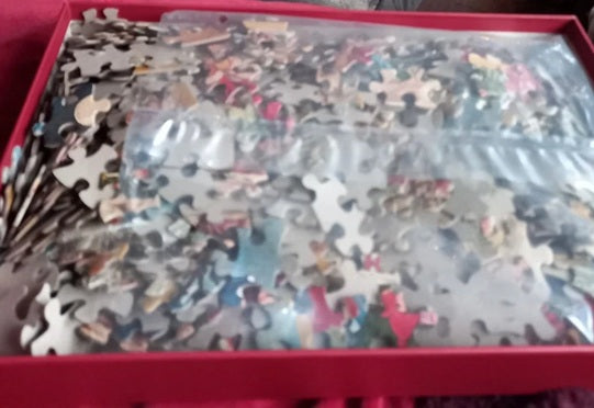 Jigsaw puzzle pieces in a box with a red lid