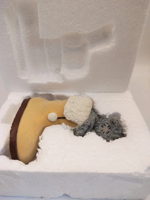 A miniature Me To You Snug Boot figurine dressed in white faux fur and a gray scarf, nestled inside white foam packaging.
