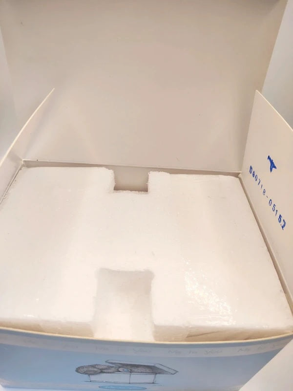 Open white product box showing white foam insert and printed packaging graphics, with a blue logo and text visible on the inner flap.