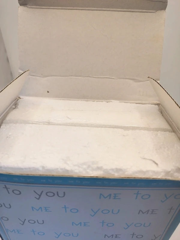 An open white cardboard gift box with a white insert, featuring a blue printed border with the words 'ME to you' repeated on the front.
