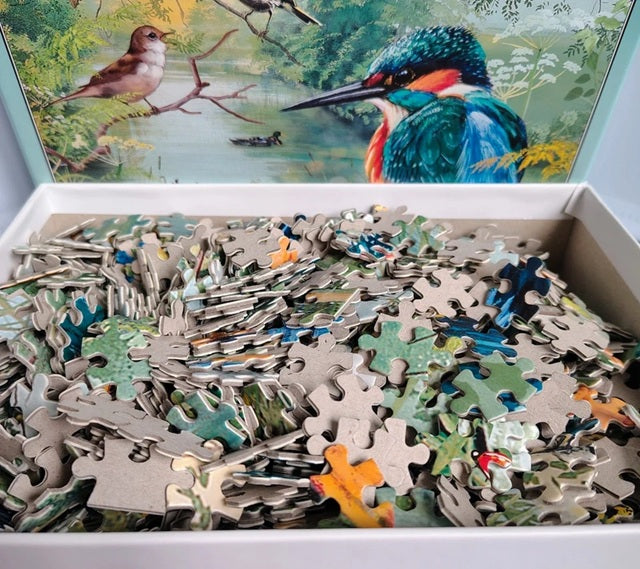 Jigsaw puzzle with pieces scattered on a table, featuring a completed puzzle of birds in the background.