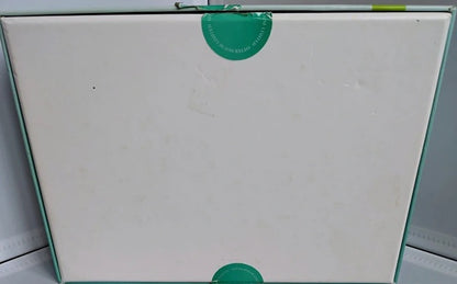 White board with a green sticker on a light gray background