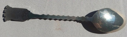 Metallic spoon with a textured handle on a gray background