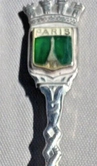 Decorative spoon with 'Paris' inscription and green gemstone, on a dark background