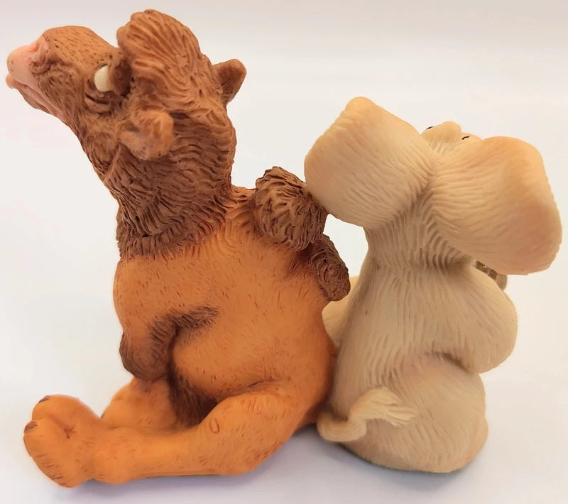 A pair of novelty figurines shaped like a camel and a pig sitting back-to-back, made from resin in terracotta brown and light beige colors.