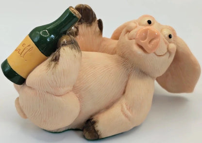 A ceramic figurine of a smiling pig lying down and holding a green wine bottle with a yellow label. Piggin Paralytic figurine. 1997 Anniversary Special. David Corbridge.
