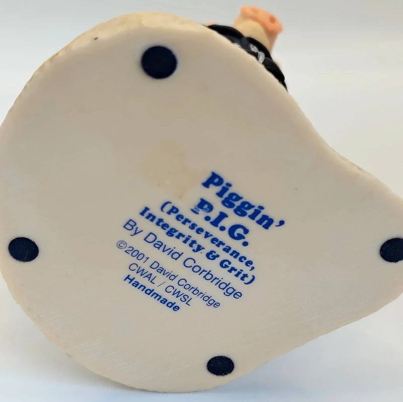 The bottom base of a ceramic Christmas ornament featuring the text 'Piggin' P.I.G