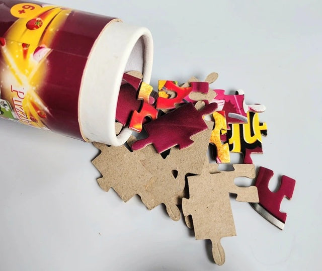 Puzzle pieces spilling out of a cylindrical container on a light gray background