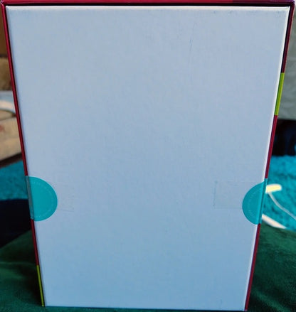 White box with red borders and blue circular design on a green surface