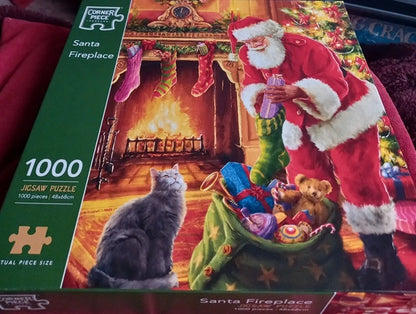 Jigsaw puzzle box featuring Santa Claus and a cat by a fireplace