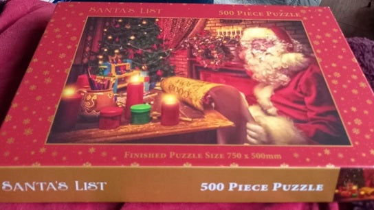 Jigsaw puzzle box featuring a Christmas scene with Santa Claus and candles on a red background.