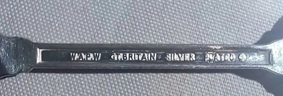 Metal wrench with engraved text on a textured gray background