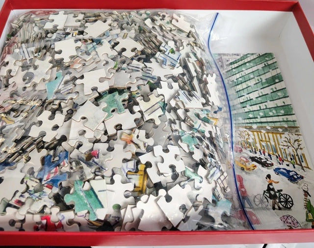 Jigsaw puzzle with pieces scattered on a box, partially completed.