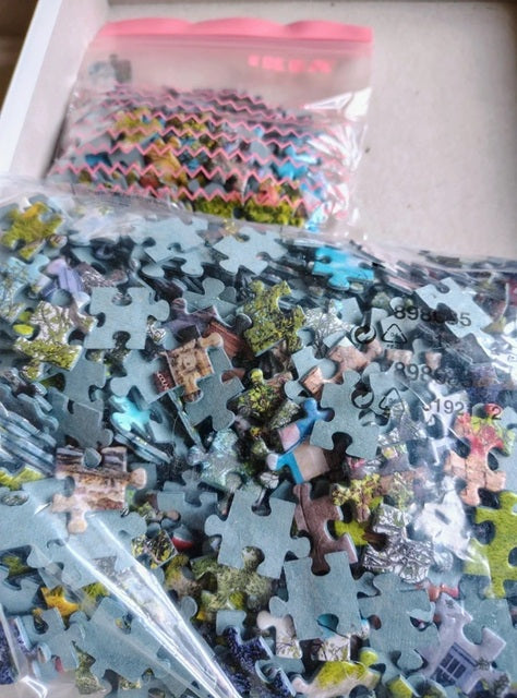 Jigsaw puzzle pieces in a clear plastic bag on a white surface